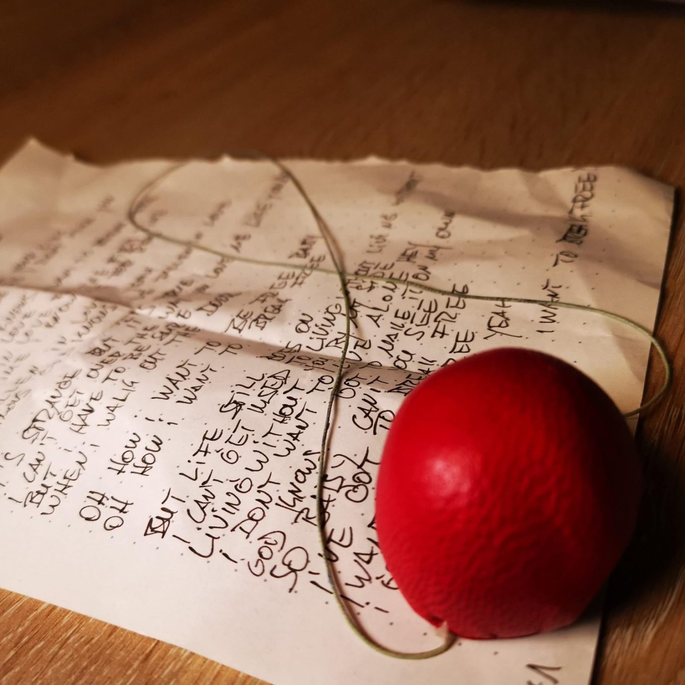 Clownarbeit clownsnase auf einem beschrifteten Papier, das auf einem Holzuntergrund liegt.